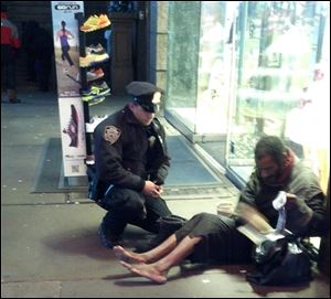 A photo provided by Jennifer Foster shows New York City Police Officer Larry DePrimo presenting a barefoot homeless man in New York's Time Square with boots Nov. 14, 2012. 