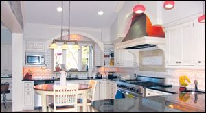 White kitchen cabinets and a white tile backsplash are reflected in the black granite countertops.