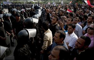Supporters of Egyptian President Mohammed Morsi chant slogans as riot police, left, stand guard in front of the entrance of Egypts top court, in Cairo.
