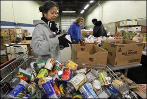 Volunteer Mylene Mendoza checks expiration dates on canned goods for clients at the Toledo Seagate Food Bank.