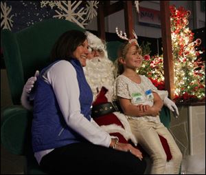 Jan Higgins and her granddaughter Leah Foreman of Holland, sit on Santa's lap at  Children’s Wonderland on Sunday. The event, a holiday treat for 49 years, is open every day, except Christmas Day, through Dec. 28.