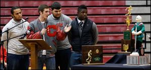 Team captains, from left, Ian Butler, Mitch Cochell, Jeff Dew, and Amir Edwards present trophies to the school. The awards are the regional and state championships and the Irish knight. 