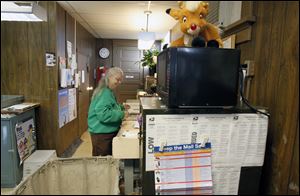 Charlotte Lamb, officer in charge, works at the mail desk while a stuffed Rudolph the Red-Nosed Reindeer sits on top of the microwave in the Rudolph Post Office. Mrs. Lamb is the lone employee at the Rudolph Post Office.