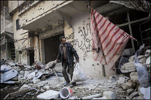 A man collects his belongings after his home was damaged due to heavy fighting between Free Syrian Army fighters and government forces in Aleppo, Syria, Sunday.
