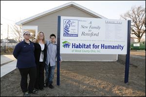 Christina Fisher flanked by her children left Alexis Sting, 17,  and right George Sting, 14, in front of their new  Habitat for Humanity home in Rossford, Ohio.