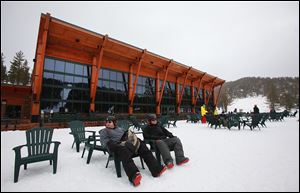 Snowboarders relax in chairs outside the Tamarack Lodge at Heavenly.