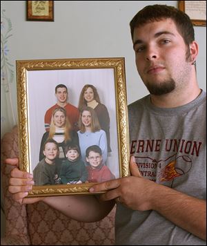 Matt Seager holds a family photo to show his twin sisters, Kimberly and Kathy, second row, who were killed in a crash on State Rt. 37. Matt Seager was driving the car, which was rear-ended