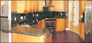 Mocha maple cabinets, Blue Volga black granite countertops, and stainless appliances make this kitchen completely on-trend. LEFT: The lighted art niche in the foyer greets visitors.