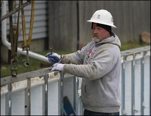 Bernie Griswold, Jr., of Clio, Mich., who works for Great Lakes Superior Walls, fastens foundation walls together on Chapin Street. Two houses there are to be finished in about  two months. They are to be sold to residents with low to moderate incomes.