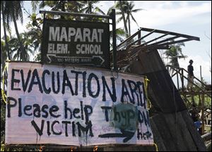 A typhoon victim rebuilds his damaged house near a sign asking for aid for victims of Typhoon Bopha at Maparat township, Compostela Valley in southern Philippines on Saturday.