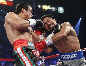 Juan Manuel Marquez, left, lands a left hook on Manny Pacquiao during their fight late Saturday night. It was the first win in four fights for Marquez against Pacquiao.