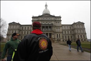 International Brotherhood of Electrical Workers members stand outside the capitol Friday in Lansing. Michigan could become the 24th state with a right-to-work law next week. Rules require a five-day wait before the House and Senate vote on each other's bills; lawmakers are scheduled to reconvene Tuesday and Gov. Rick Snyder has pledged to sign the bills into law.