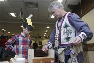Xavier Jackey, 10, of Moline, Ohio, watches Brian Jensen work with loom beads during the Fort Meigs Holiday Open House.
