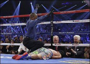 Referee Kenny Bayless calls the fight as he kneels over Manny Pacquiao after he was knocked out by Juan Manuel Marquez during their WBO world welterweight  fight Saturday in Las Vegas.