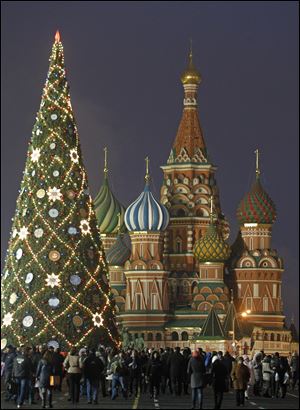 People walk in Moscow's Red Square decorated for New Year and Christmas celebrations, with St. Basil Cathedral in the background.