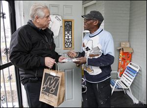 Mobile Meals of Toledo volunteer driver Jim Szymanski delivers a meal bag to Elgin Rogers, at his home Friday in Toledo.