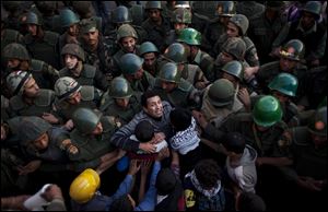 Egyptian protesters push against soldiers in front of the presidential palace in Cairo. Egypt’s liberal opposition called for more protests on Tuesday.