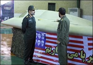 A photo released in December, 2011, by the Iranian Revolutionary Guards, purports to show the chief of the aerospace division of Iran's Revolutionary Guards, Gen. Amir Ali Hajizadeh, left, listening to an unidentified colonel pointing to a U.S. RQ-170 Sentinel drone which Tehran says its forces downed. 