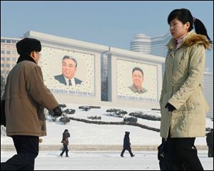 North Koreans walk by the portraits of they country's national founder Kim Il Sung, left, and late leader Kim Jong Il in Pyongyang, North Korea today.