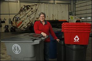 Program coordinator for Perrysburg's Office of Litter Prevention and Recycling Judy Hagen stands with, on the left, one of the new totes that will serve as the city's trash and recycling bins. On the right are the old bins, both smaller than the new models.
