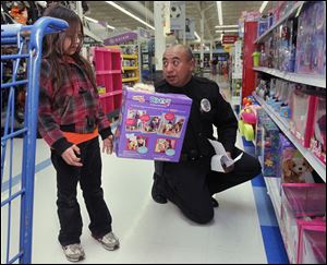 Cygnet, Ohio, resident Brooklyn McKee, 7, shops with Owens Community College police officer Luis Munguia during a shopping spree at Meijer in Rossford, Ohio.