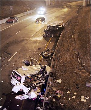 A white van carrying a family of eight from Maryland lies crumpled against a guardrail on southbound I-280 near the Manhaten Blvd. exit in Toledo, Ohio in 2007. 5 members of the Maryland family died when a dark colored pickup shown against the guardrail (center)  traveled the wrong way on the four-lane highway.