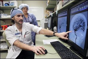 Dr. John Whapham, a neuroendovascular surgeon, describes the aneurysm coiling procedure performed on Olivia Cox, behind him.