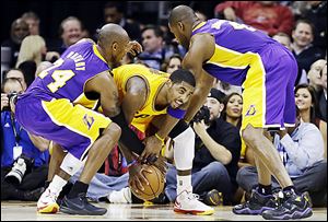 The Lakers’ Kobe Bryant, left, and Antawn Jamison, right, attempt to slow Cavaliers point guard Kyrie Irving, who scored 28 points in a home victory.