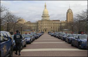 Michigan State Police cruisers line the pedestrian walkway west of the state Capitol in Lansing, Mich., Monday.