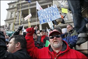 Demonstrators including Ron Sparks of Flint, Michigan, right, protest against right to work legislation at the Michigan State Capitol.