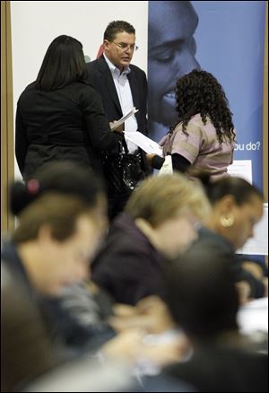 Job seekers surround Tim Taylor of Manpower Inc. of Toledo at a job fair at Seagate Convention Centre this fall. Manpower's hiring outlook for 2013 is similar to this year's.