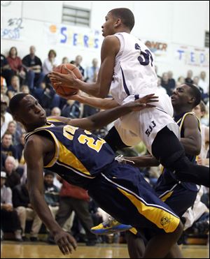 Marc Loving of St. John's charges over Whitmer's Nigel Hayes in Wednesday's Three Rivers Athletic Conference game. Loving finished with 22 points, while Hayes had 19.