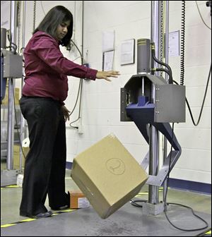 UPS packaging engineer Preeti Agrawal uses a drop impact tester that simulates a box traveling through the small parcel system at the UPS Package Design and Testing Lab in Addison, Ill. UPS tests new packaging designs by dropping, shaking, and smashing boxes.