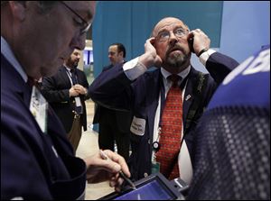 FILE - In this Tuesday, Dec. 11, 2012, file photo, Trader Frederick Reimer, right, works on the floor of the New York Stock Exchange. Stocks opened close to break-even Thursday after the government said weekly applications for unemployment benefits fell to the second-lowest level this year. (AP Photo/Richard Drew, file)