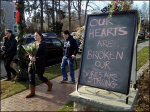 A chalked sign outside a downtown business reflects the emotions in Newtown, Conn., after the massacre. Similar signs have sprung up throughout the city of 26,000.