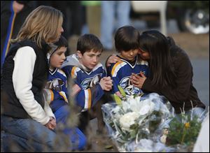 From left, Jean Bradley, Steven Turchetta, 9, Jean's son Matthew Bradley, 9, Ashton Baltes, 10, and his mother Elonda Baltes pay their respects today at a memorial for shooting victims near Sandy Hook Elementary School.