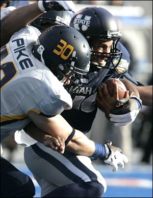 Utah State's Chuck Jacobs runs against the defense of Toledo's Ben Pike today in Boise, Idaho.