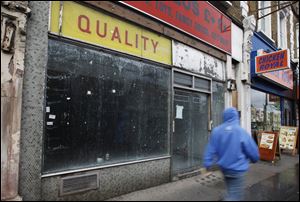 A pedestrian passes a closed down shop in London in April. Britain's economy fall back into recession for the first time since 2009 after official figures showed that it unexpectedly contracted during the first three months of 2012.