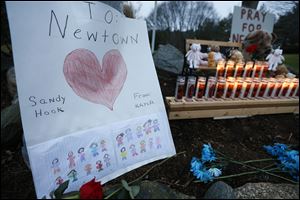 A child's message rests with a memorial for shooting victims, Sunday, in Newtown, Conn. 