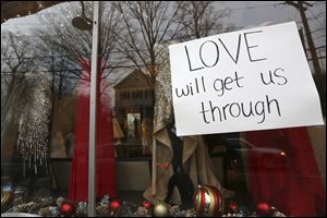 A sign hangs in the window of a clothing store today in Newtown, Conn. On Friday, a gunman allegedly killed his mother at their home and then opened fire inside the Sandy Hook Elementary School, killing 26 people, including 20 children.