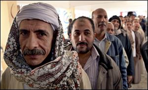 Egyptian men line up outside a polling station to cast their votes during a referendum on a disputed constitution drafted by Islamist supporters of President Morsi in Cairo.