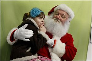 Dave Davis of Sylvania waits to hear the Christmas wishes of Danielle Tiller, 6, during a recent event. He said he gets a lot of questions about the reindeer, but he said it is rare for a child to ask whether Santa is real. What isn’t rare, he said, is the look of fascination  on a child’s face.