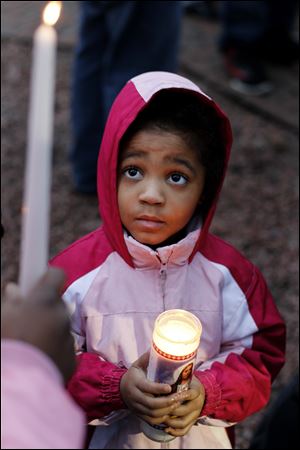Princess Blackman, 6, clutches a candle as she attends the vigil at the Toledo Children's Memorial.