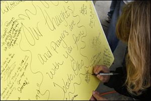 Shannon Falk of Springfield Township signs a card during a memorial event in West Toledo.