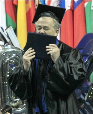 Paul Manol of Sylvania kisses his diploma after graduating magna cum laude with a bachelor of science degree from UT's college of lifelong learning. 