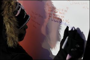 Savonna Thompson, 8, writes a message to the victims during the vigil at the Toledo Children's Memorial. 