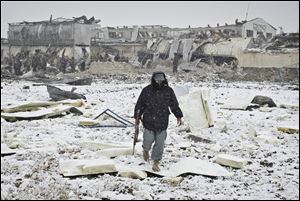 An Afghan policeman walks in rubble caused by a car bomb explosion in Kabul, Afghanistan, today.