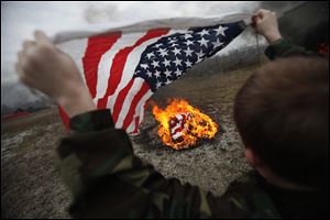 Robert Brushaber, 11, prepares to commit a flag to the flames.  Dozens gathered in Perrysburg Township for Sunday’s ceremony.