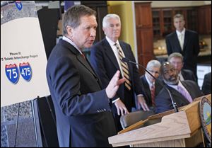 Ohio Gov. John Kasich speaks in Toledo on Thursday about Ohio Turnpike plans. Standing, center, is ODOT Director Jerry Wray. Mayor Mike Bell is seated at right. 