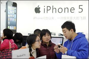 A storekeeper introduces iPhones to customers near an iPhone 5 advertisement at an Apple products shop in Dongyang, in eastern China's Zhejiang province, Friday.
